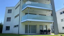 modern white building, 3 stories, multiple balconies, glass windows, outdoor dining area