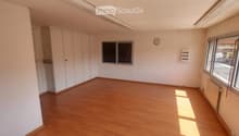 Empty room with wooden flooring, white walls, built-in wardrobes, and large windows allowing natural light.