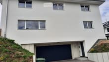 Modern two-story house with white exterior, large windows, and a dark garage door.