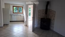 Bright room with tiled floor, fireplace, and an open doorway leading to another room with a window and kitchen area.