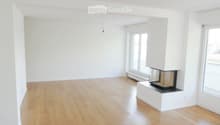 Empty room with light wooden flooring, white walls, and a built-in fireplace with a glass front.