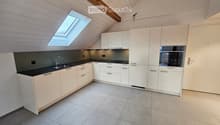 white kitchen cabinets, grey floor tiles, black countertops, stainless steel sink, dishwasher, built-in oven, skylight
