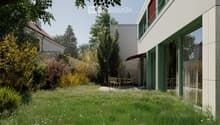 A modern garden area with a lawn, small trees, and a patio with outdoor furniture near a contemporary building.