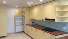Modern kitchen with light-colored cabinets, a stainless steel sink, and a built-in stove. The refrigerator is open, revealing its interior.
