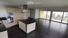 Modern kitchen with white cabinets, black countertops, induction cooktop, and large sliding glass doors leading to a balcony.