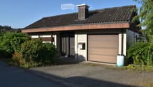 Two-story house with a tiled roof, garage, and a small garden area.