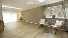 Empty room with wooden flooring, large windows, and neutral-colored walls. No furniture or equipment present.