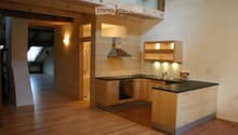 Modern kitchen with wooden cabinets, stainless steel appliances, and a black countertop. Features include a stove, oven, sink, range hood, and built-in lighting.