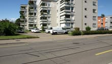 An apartment building with multiple balconies, parking space for several cars.