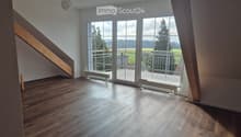 Empty room with wooden flooring, large windows, and a staircase leading upwards.