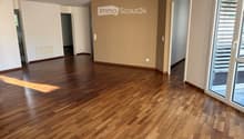 Empty room with polished wooden flooring, white walls, and large windows with blinds. No furniture or equipment present.