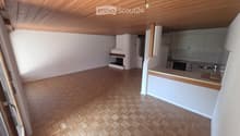 Open-plan living and kitchen area with wooden herringbone flooring, white cabinets, a kitchen counter, sink, faucet, oven, and a fireplace.