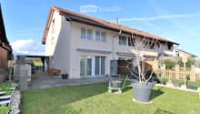Well-maintained garden with a lawn, potted plants, a barbecue area, and a patio with outdoor furniture.