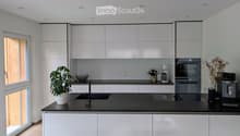 Modern kitchen with white cabinets, black countertop, sink, coffee maker, oven, and decorative plant.