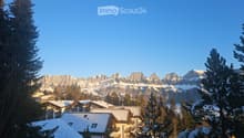 Mountainous area with snow-covered buildings and a snowy mountain range in the background.