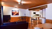 Open living room, sofa, wooden dining table, kitchen island, dining chairs, TV, painting on wall, ceiling light, fan
