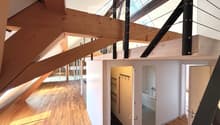 Open hallway with wooden flooring, white walls, and visible rooms including a bathroom with a bathtub and a closet with hanging space.