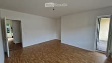 Empty room with wooden flooring, white walls, and large sliding glass doors leading to a balcony or outdoor area.