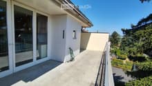 Balcony with concrete floor, glass sliding doors, metal railing, and a view of greenery and trees.