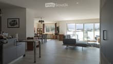Open-plan living and dining area with modern furniture, large windows, and a view of the landscape.