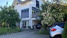 Two-story house with white exterior, garage, balcony, and driveway with parked cars.