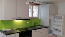 Modern kitchen with white cabinets, black countertops, induction cooktop, sink, and open refrigerator.