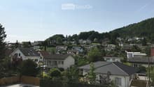 Residential neighborhood with multiple houses, surrounded by greenery and trees, with a clear view of the surrounding landscape.