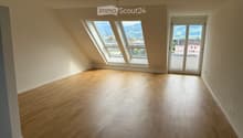 Empty room with wooden flooring, large windows, and a sliding glass door leading to a balcony.