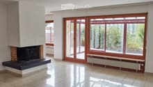 Empty living room with tiled floor, large windows, fireplace, radiator, and sliding glass doors leading to a balcony.