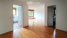 Empty room with wooden flooring and white walls, featuring three open doorways leading to other rooms.