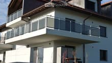 Two-story house with a balcony, modern design, and a small outdoor seating area with a table and chairs.