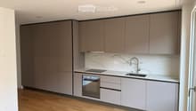 Modern kitchen with grey cabinets, marble backsplash, and wooden flooring.