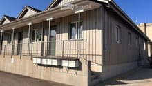Two-story wooden building with a balcony, mailboxes, and a parking sign.