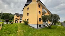 2 story yellow house, white trim, multiple balconies, large grassy yard