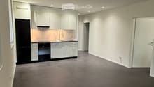 Empty kitchen with white cabinets, black appliances, and dark tiled flooring.