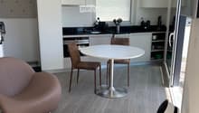 open plan kitchen with dining area, modern style, large dining table with 4 chairs, stainless steel kitchen island with sink, white cabinets, modern pendant light, wooden floor, open door, white sheet on bed