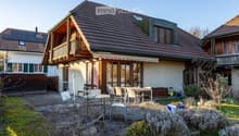 Detached house, brown roof, wooden balcony, solar panels, garden, outdoor dining area