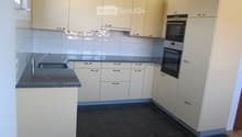 Modern kitchen with light-colored cabinets, dark tiled floor, granite countertop, and built-in oven.