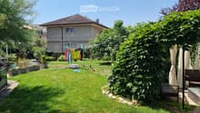 Well-maintained garden with a lawn, potted plants, a clothesline with laundry, and a small seating area with outdoor furniture.