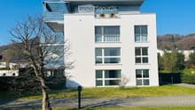 modern white house, 3 floors, large windows, balcony on the top floor, solar panels on the roof
