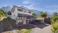 Two-story modern house with white exterior, large windows, balcony, garage, and scenic mountain view.