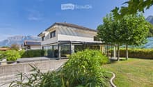 Modern two-story house with white exterior, large windows, and a spacious garden with well-maintained lawn and greenery.