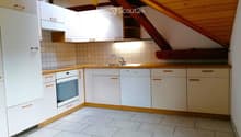 Modern kitchen with white cabinets, wooden accents, tiled walls, and a stainless steel sink and faucet.