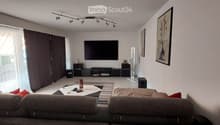 Modern living room with a grey sofa, coffee table, television, fan, and picture frame on the wall.