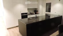 Modern kitchen with white cabinets, black countertops, stainless steel sink, and various appliances including an oven, toaster, and coffee maker.