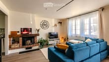 Modern living room with a blue sectional sofa, fireplace, television, coffee table, floor lamp, and decorative items.