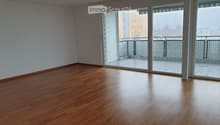 Empty room with wooden flooring and large sliding glass doors leading to a balcony.