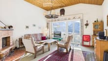 Cozy living room with a fireplace, large window offering a mountain view, sofa, armchairs, coffee table, television, and decorative items.