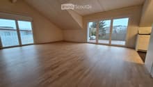 Empty attic room with wooden flooring, large windows, and sliding doors leading to a terrace.
