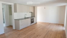 Modern kitchen with light-colored cabinets, a black countertop, and a wooden floor. The kitchen features a sink, oven, and ample storage space.